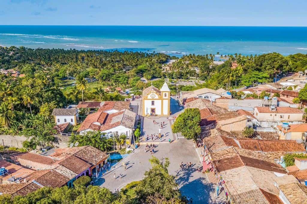 Vista aérea do Centro Histórico de Arraial d'Ajuda com a Igreja Nossa Senhora d'Ajuda e o mar ao fundo Vista aérea do Centro Histórico de Arraial d'Ajuda com a Igreja Nossa Senhora d'Ajuda e o mar ao fundo