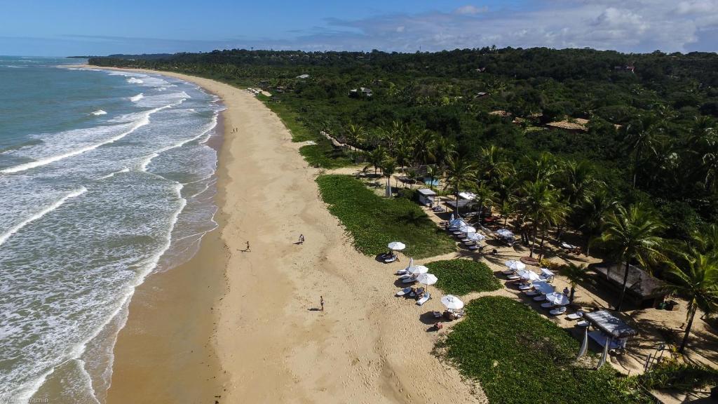 Vista aérea da Praia dos Nativos em Trancoso, mostrando a faixa de areia, o mar calmo e a vegetação preservada em frente ao Hotel Villas de Trancoso Vista aérea da Praia dos Nativos em Trancoso, mostrando a faixa de areia, o mar calmo e a vegetação preservada em frente ao Hotel Villas de Trancoso