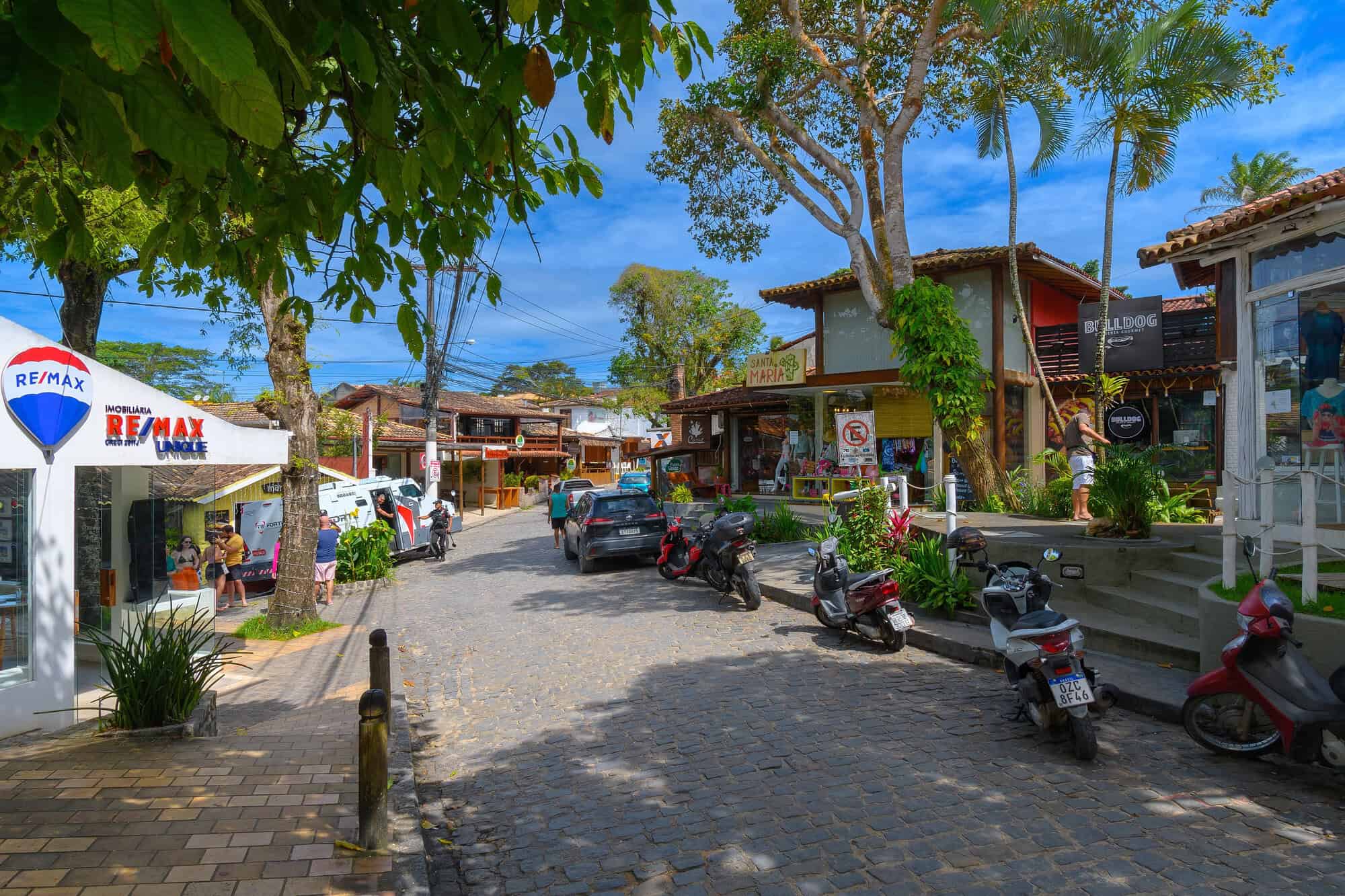 Rua do Mucugê em Arraial d'Ajuda com lojas, bares e restaurantes em dia ensolarado