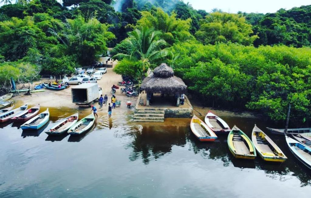 Vista aérea e panorâmica do porto de travessia das canoas em Nova Caraíva. Mostra o Rio Caraíva, dezenas de canoas coloridas atracadas, uma cabana de apoio, carros e vans estacionados e a movimentação de turistas no lado do continente Vista aérea e panorâmica do porto de travessia das canoas em Nova Caraíva. Mostra o Rio Caraíva, dezenas de canoas coloridas atracadas, uma cabana de apoio, carros e vans estacionados e a movimentação de turistas no lado do continente