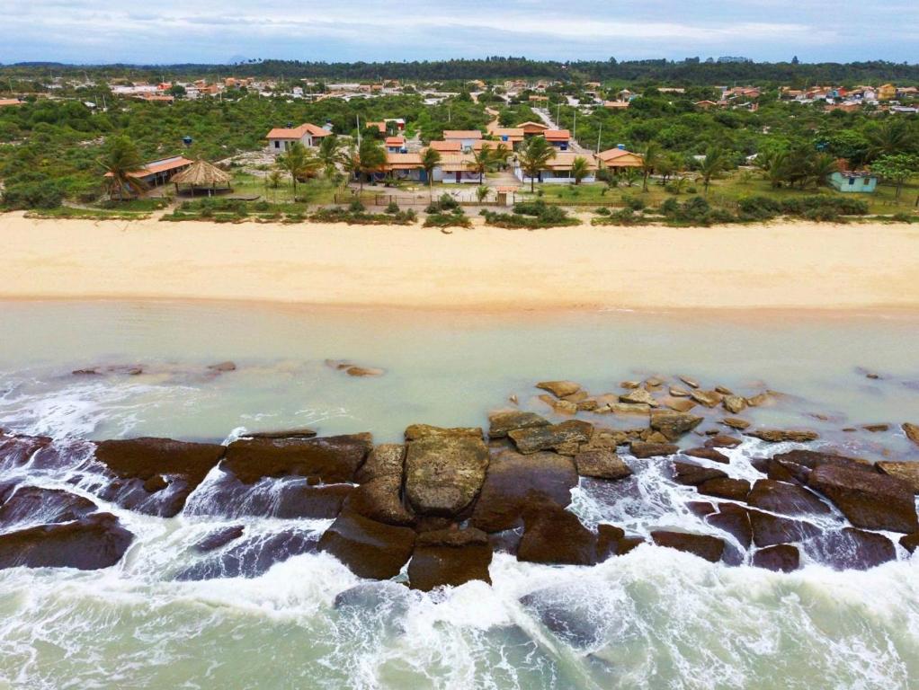 Vista aérea da praia da Aldeia Xandó em Caraíva, mostrando a faixa de areia dourada, recifes de corais na água e a pousada OCA Caraíva cercada por vegetação nativa ao fundo Vista aérea da praia da Aldeia Xandó em Caraíva, mostrando a faixa de areia dourada, recifes de corais na água e a pousada OCA Caraíva cercada por vegetação nativa ao fundo